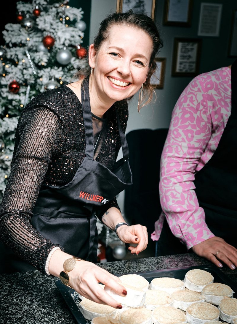 Impressionen vom gemeinsamen Kochen bei der Weihnachtsfeier der Kanzlei – Mitarbeiterin kocht und lacht in die Kamera