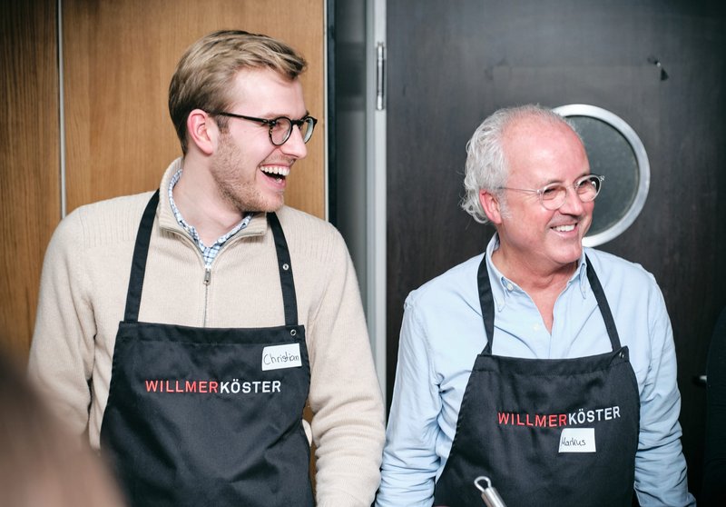 Impressionen vom gemeinsamen Kochen bei der Weihnachtsfeier der Kanzlei – Zwei Mitarbeiter lachen